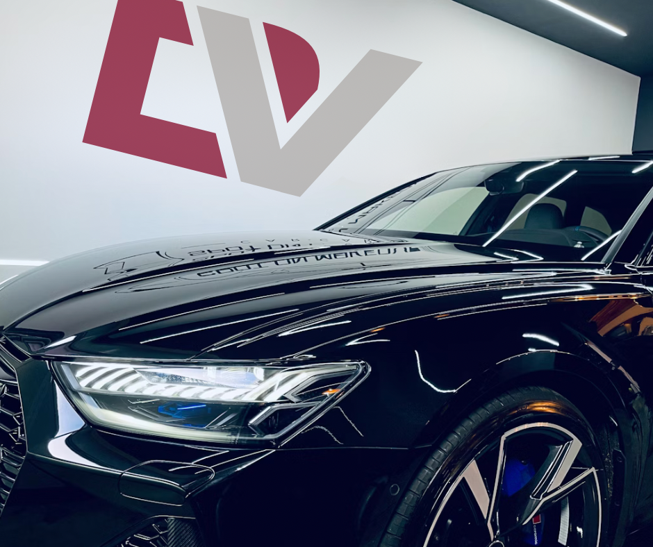 Close-up of a glossy black Audi with sharp reflections inside Detailing Valet studio, featuring the DV logo on the wall